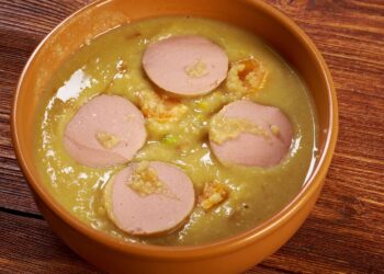 Dikke erwtensoep vol groenten, kruiden en sappige rookworst