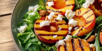 Frisse zomersalade met warme perzik, knapperige amandelen en feta met balsamicodressing